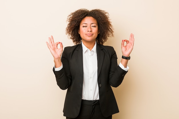 La giovane donna afroamericana di affari si rilassa dopo la dura giornata lavorativa, sta eseguendo l'yoga.