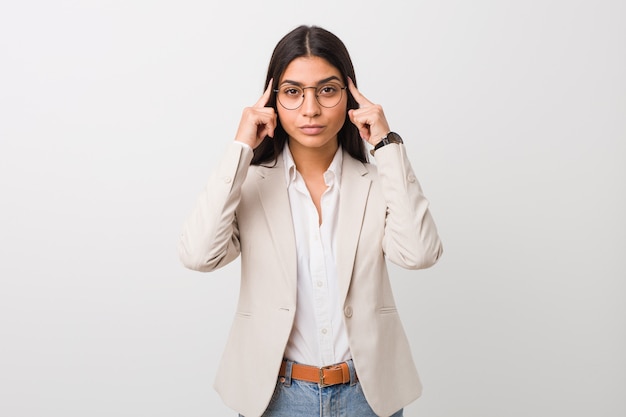 Young business arab woman isolated against a white background focused on a task, keeping forefingers pointing head.