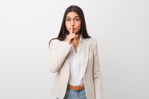 Young business arab woman isolated against a white wall keeping a secret or asking for silence.