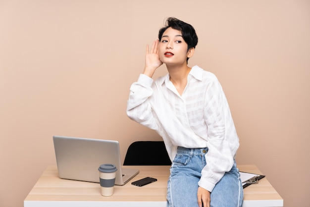 Young business Asian woman in her workplace listening something