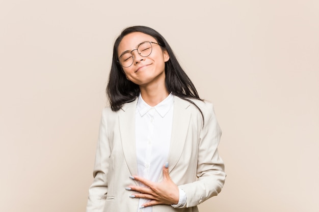 Young business asian woman touches tummy, smiles gently