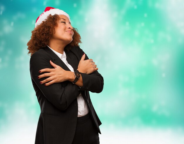 Young business black woman wearing a chirstmas santa hat giving a hug