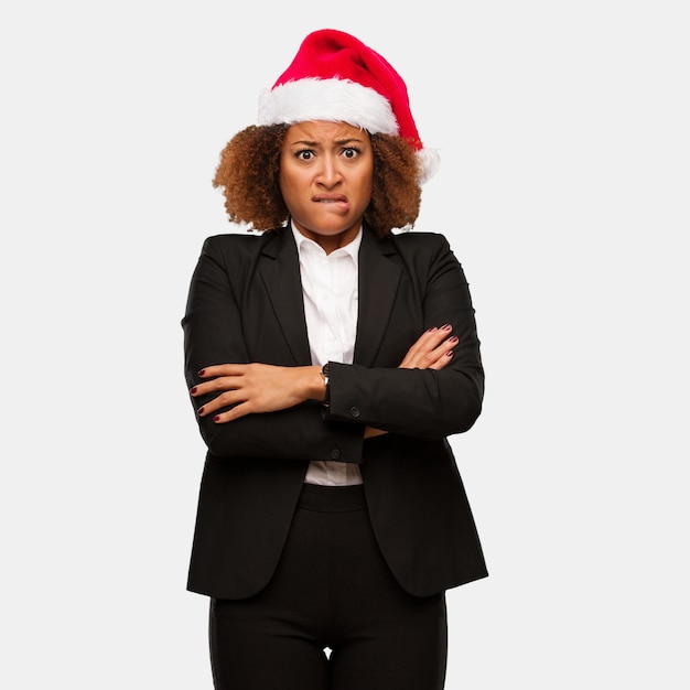 Young business black woman wearing a chirstmas santa hat thinking about an idea