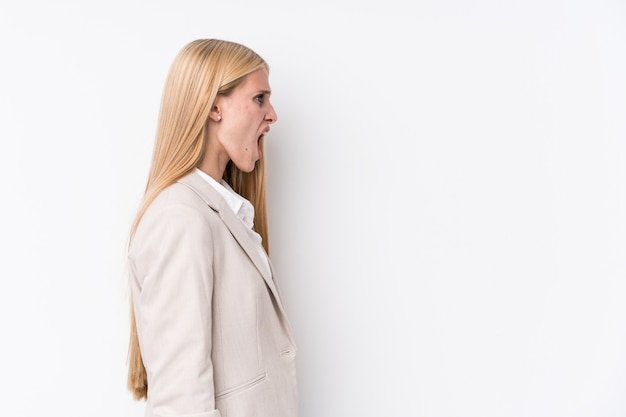 Young business blonde woman on white wall shouting towards a copy space