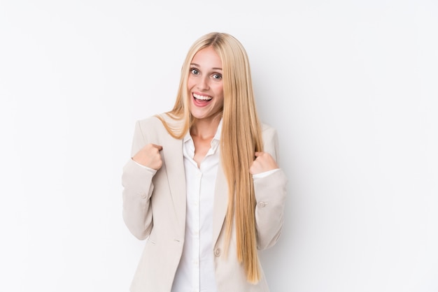 Young business blonde woman on white wall surprised pointing with finger