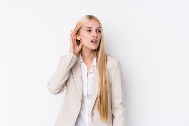 Young business blonde woman on white wall trying to listening a gossip.