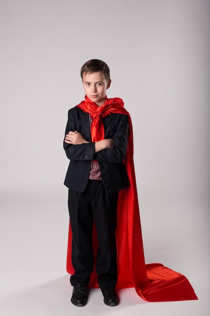 Young business boy in red superhero cape