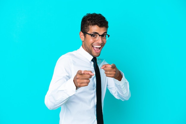 Young business Brazilian man isolated on blue background pointing to the front and smiling