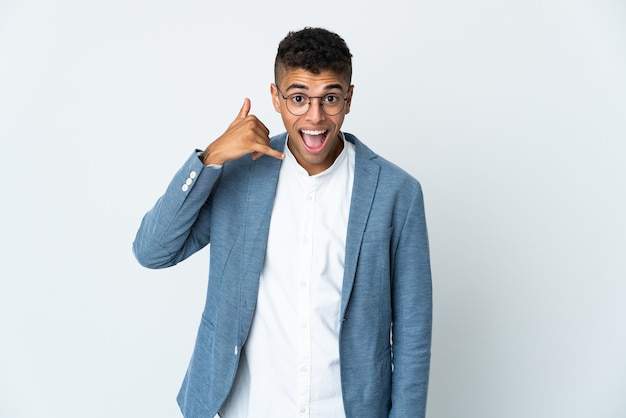 Young business Brazilian man on white background making phone gesture. Call me back sign