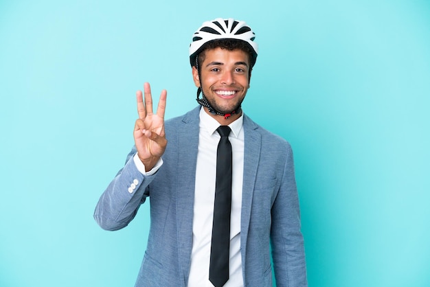 Young business Brazilian man with bike helmet isolated on blue background happy and counting three with fingers