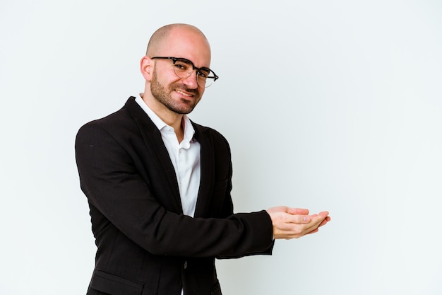 Young business caucasian bald man isolated on blue background holding a copy space on a palm.