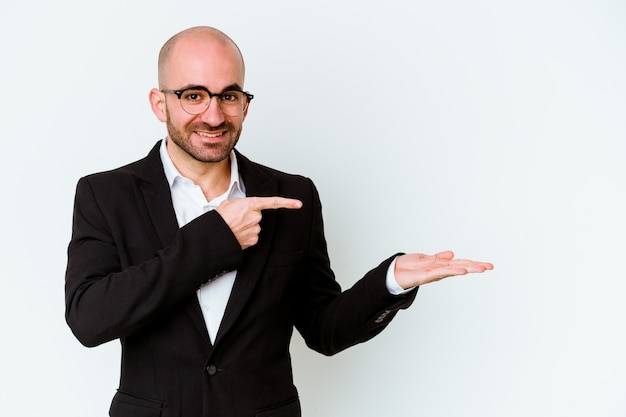 Young business caucasian bald man isolated on white wall excited holding a copy space on palm.