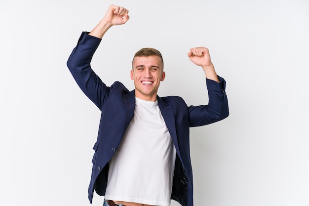 Young business caucasian man celebrating a special day, jumps and raise arms with energy.