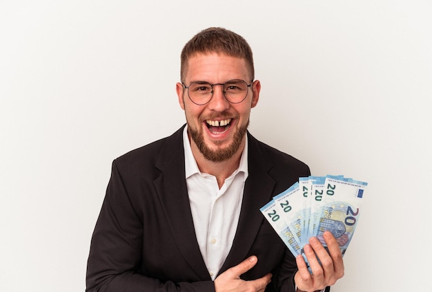 Young business caucasian man holding banknotes isolated on white background laughing and having fun.