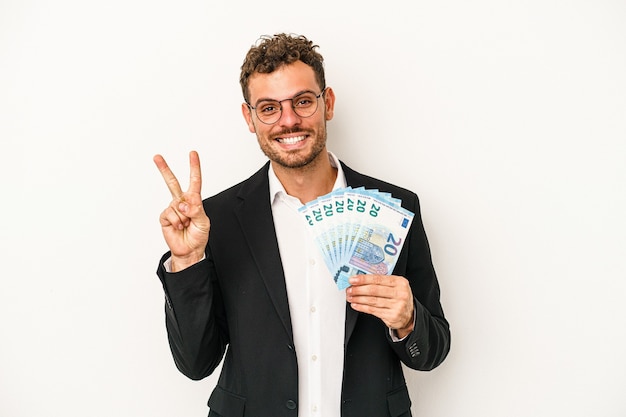 Young business caucasian man holding banknotes isolated on white background showing number two with fingers.