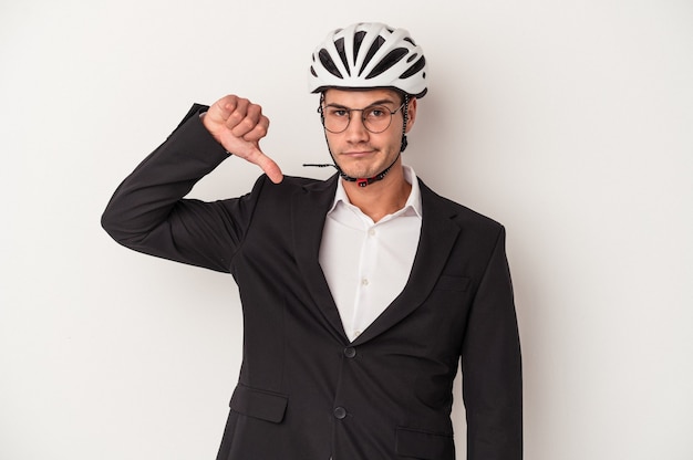 흰색 배경에 격리된 자전거 헬멧을 들고 있는 백인 젊은 사업가는 싫어한다는 제스처를 보이고 엄지손가락을 아래로 내립니다. 불일치 개념입니다.