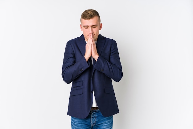 Young business caucasian man holding hands in pray near mouth, feels confident.
