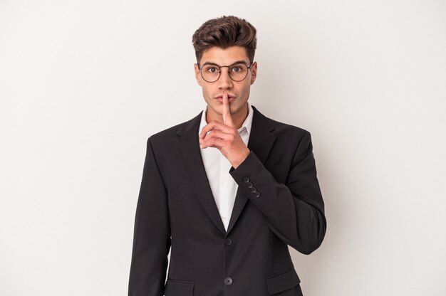 Young business caucasian man isolated on white background keeping a secret or asking for silence.