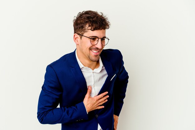 Young business caucasian man isolated on white background laughing keeping hands on heart, concept of happiness.