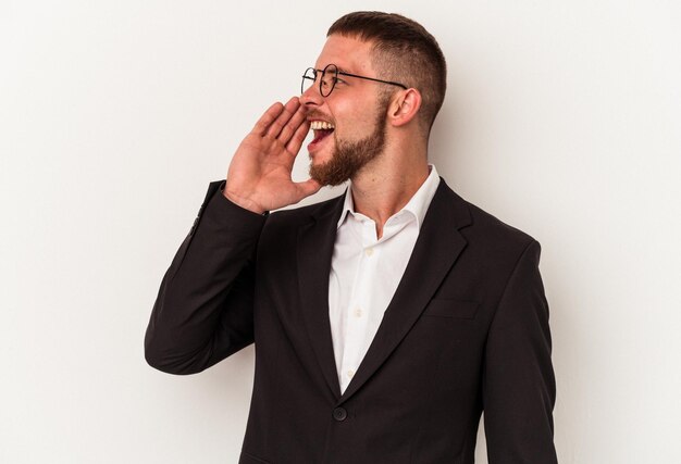 Young business caucasian man isolated on white background shouting and holding palm near opened mouth.