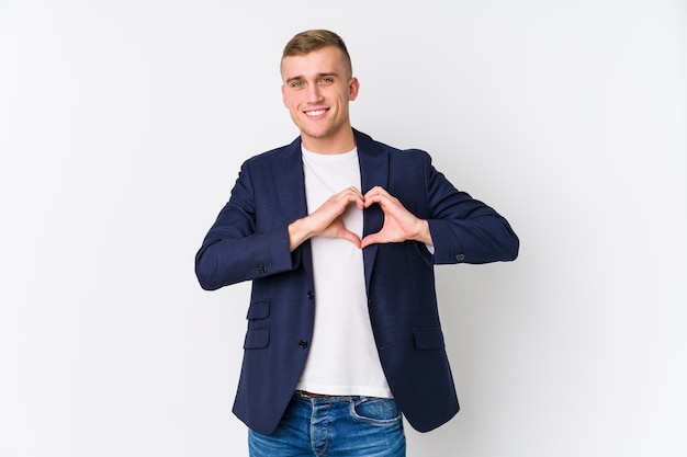 Young business caucasian man smiling and showing a heart shape with hands.