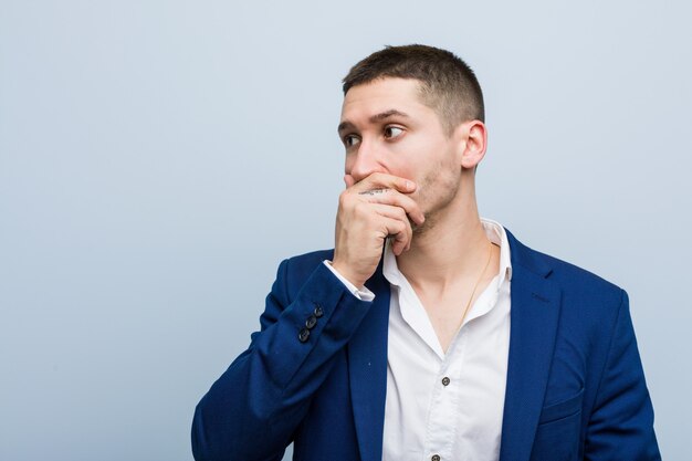 Young business caucasian man thoughtful looking to a copy space covering mouth with hand.