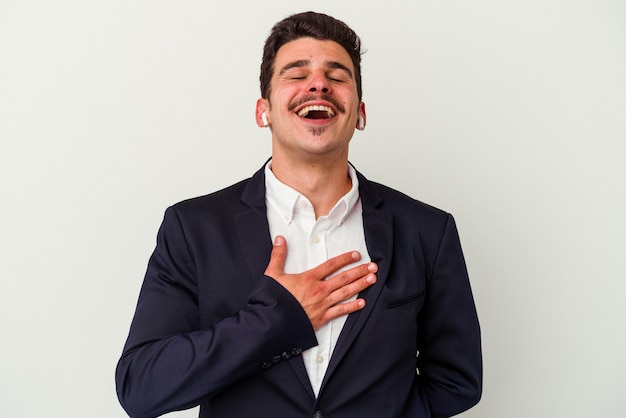 Young business caucasian man wearing wireless headphones isolated on white background laughs out loudly keeping hand on chest.