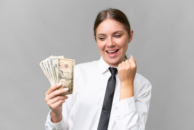 Young business caucasian woman holding money over isolated background celebrating a victory