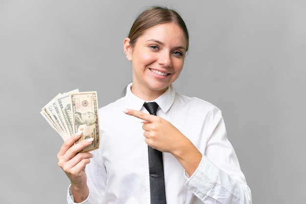 Young business caucasian woman holding money over isolated background and pointing it