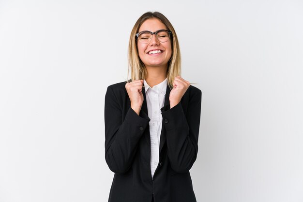 Young business caucasian woman raising fist, feeling happy and successful. Victory concept.