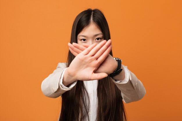 Young business chinese woman doing a denial gesture