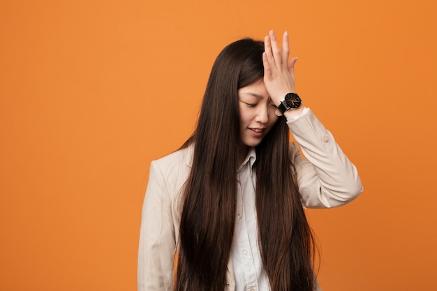 Young business chinese woman forgetting something, slapping forehead with palm and closing eyes.