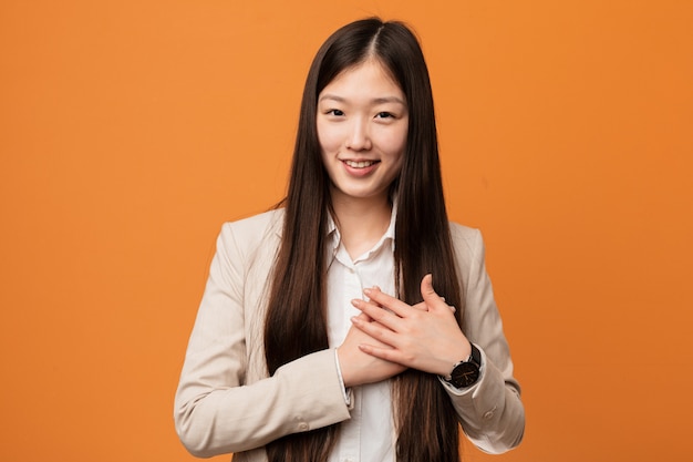 Young business chinese woman has friendly expression, pressing palm to chest. Love concept.