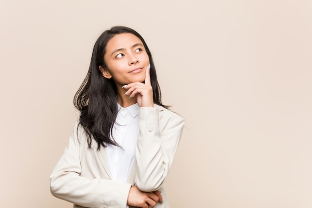 Photo young business chinese woman looking sideways with doubtful and skeptical expression.