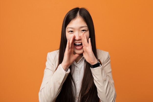 Young business chinese woman shouting excited to front.