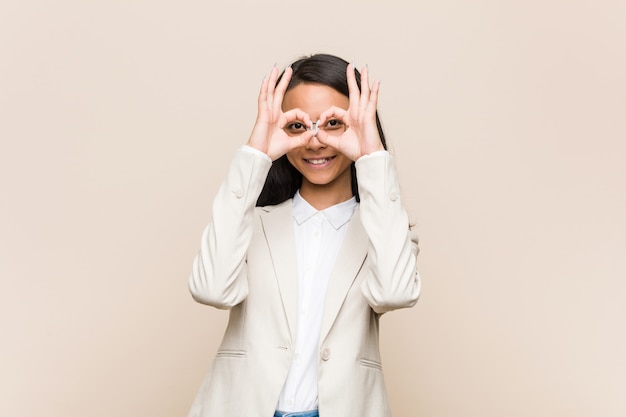 Young business chinese woman showing okay sign over eyes