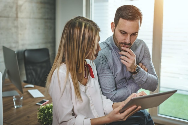 I giovani colleghi di lavoro stanno analizzando il progetto e ne parlano mentre utilizzano la tavoletta digitale in ufficio.