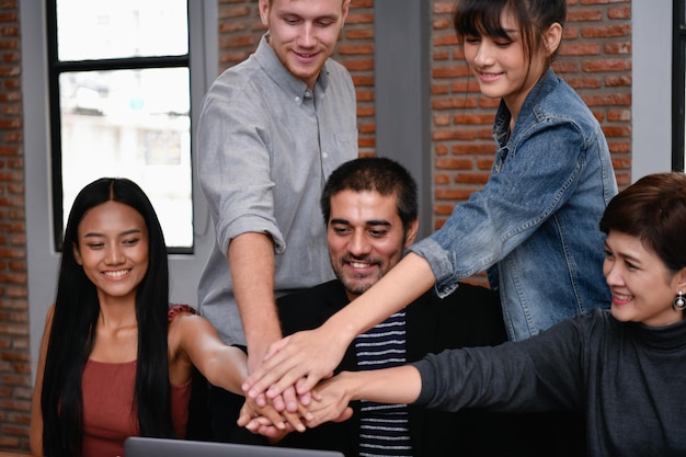 young business colleagues joining hands in office