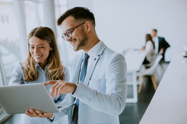 Young business couple working and discussing by laptop in the office in front of their team