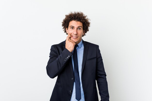 Young business curly man against white background biting fingernails, nervous and very anxious.