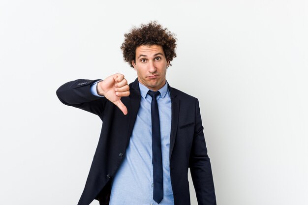 Young business curly man against white background showing a dislike gesture, thumbs down