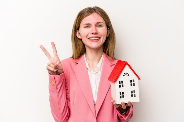 Young business English woman holding house toy isolated on white background showing number two with fingers