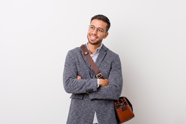 Young business filipino man against a white wall smiling confident with crossed arms.