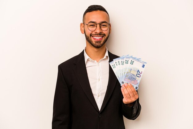 Young business hispanic man holding banknotes isolated on white background happy smiling and cheerful