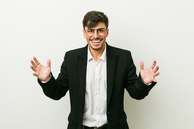 Young business hispanic man receiving a pleasant surprise, excited and raising hands.