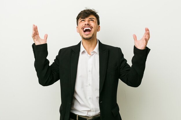 Young business hispanic man screaming to the sky, looking up, frustrated.