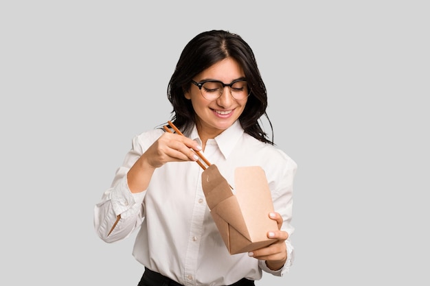 Young business indian woman eating takeaway noodles cut out isolated