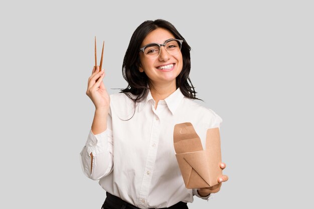 Young business indian woman eating takeaway noodles cut out isolated