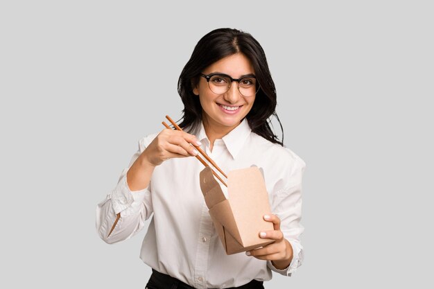 Young business indian woman eating takeaway noodles cut out isolated