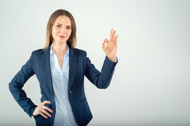 Young business lady shows ok sign isolated on grey background